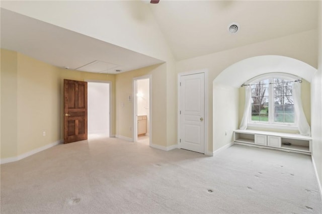 spare room with lofted ceiling, baseboards, attic access, light colored carpet, and a ceiling fan