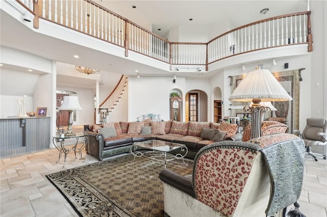 living room featuring stairs, a high ceiling, a wealth of natural light, and stone tile flooring