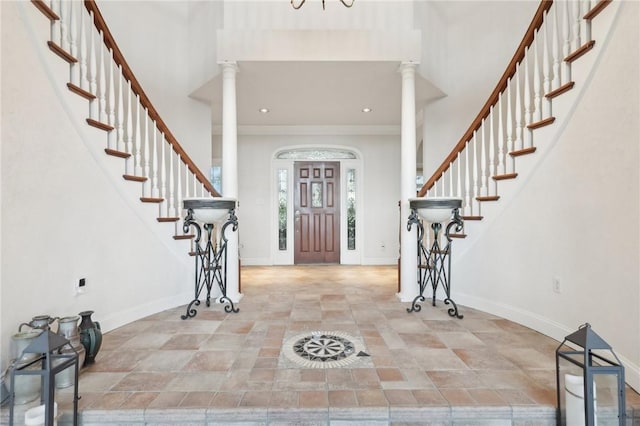 foyer with baseboards, stone finish floor, decorative columns, and stairs