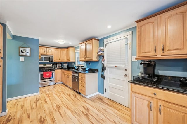 kitchen with light hardwood / wood-style floors, sink, stainless steel appliances, and dark stone counters