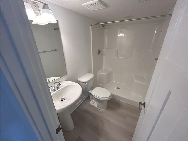 bathroom featuring wood-type flooring, toilet, walk in shower, and sink