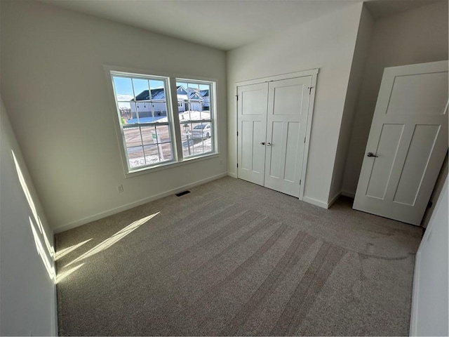 unfurnished bedroom featuring light carpet and a closet