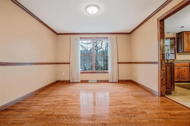 spare room featuring light hardwood / wood-style flooring and crown molding