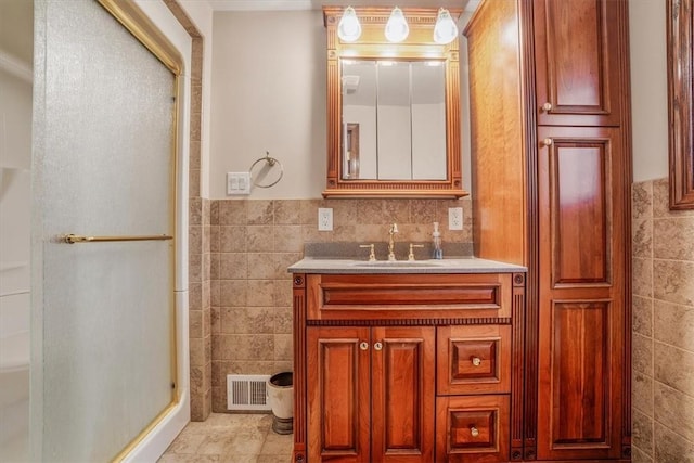 bathroom featuring tile patterned flooring, vanity, an enclosed shower, and tile walls