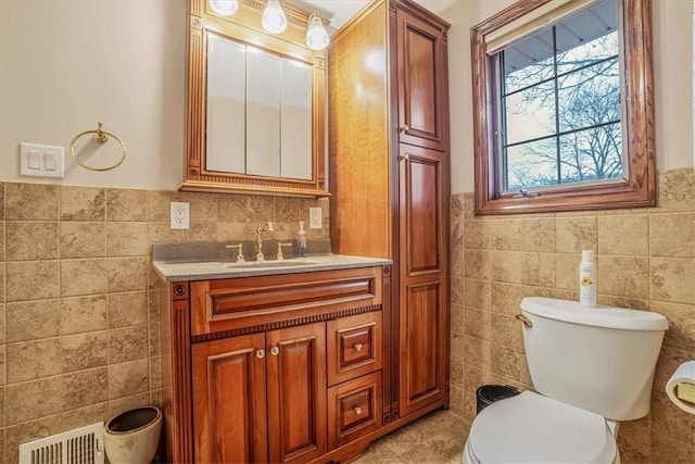 bathroom featuring vanity, toilet, and tile walls