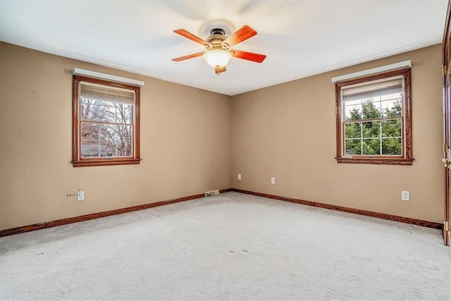 empty room featuring plenty of natural light, ceiling fan, and light colored carpet