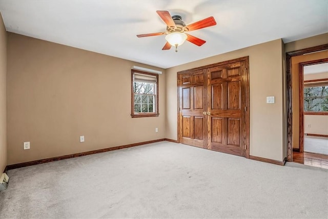 unfurnished bedroom featuring light carpet, multiple windows, and ceiling fan