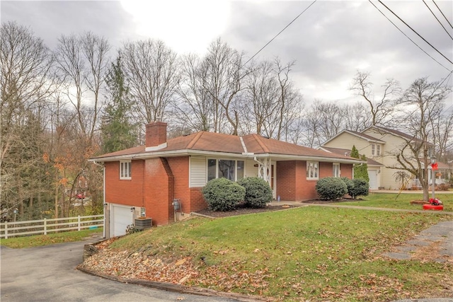 view of front of property featuring a garage, a front lawn, and central air condition unit