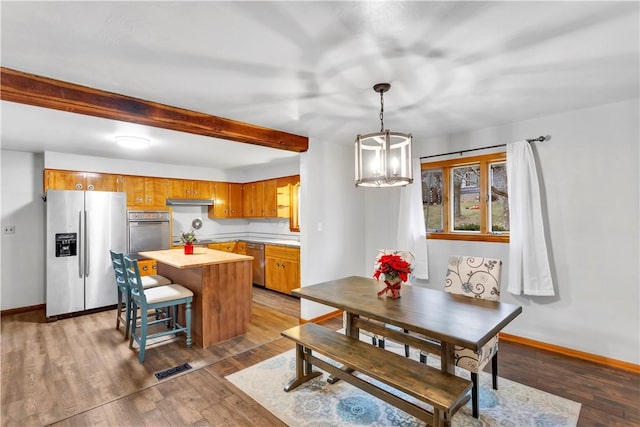 kitchen featuring stainless steel appliances, wood-type flooring, pendant lighting, beamed ceiling, and a chandelier