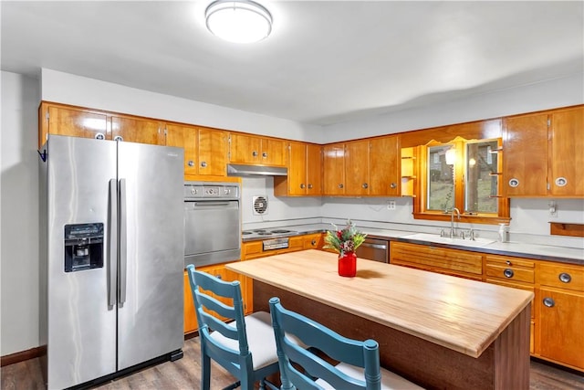 kitchen with sink, a kitchen island, dark hardwood / wood-style flooring, and stainless steel appliances