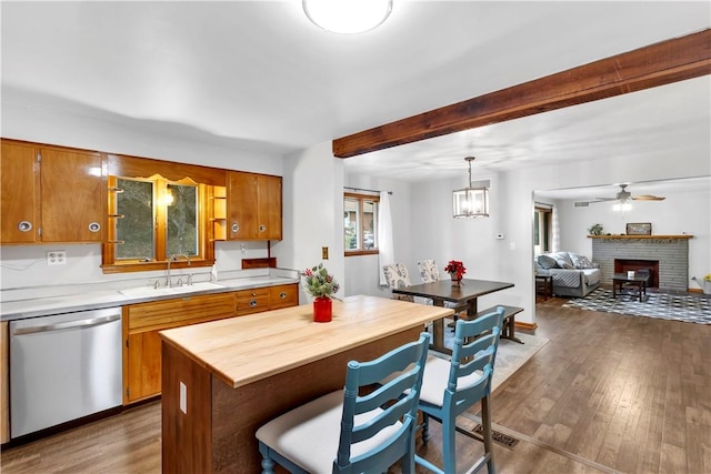 kitchen with a center island, dark wood-type flooring, sink, stainless steel dishwasher, and a fireplace