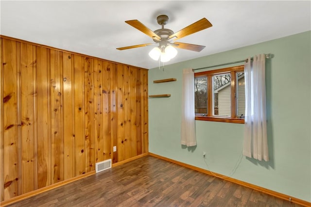 spare room with wood walls, ceiling fan, and dark hardwood / wood-style floors