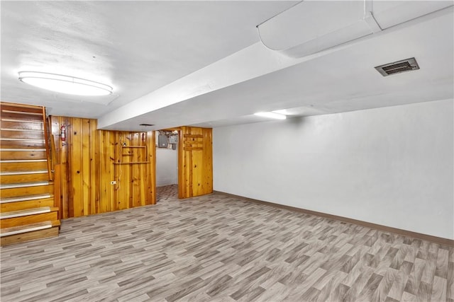 basement with wooden walls and light hardwood / wood-style flooring