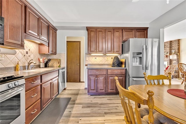 kitchen featuring backsplash, sink, light wood-type flooring, and appliances with stainless steel finishes