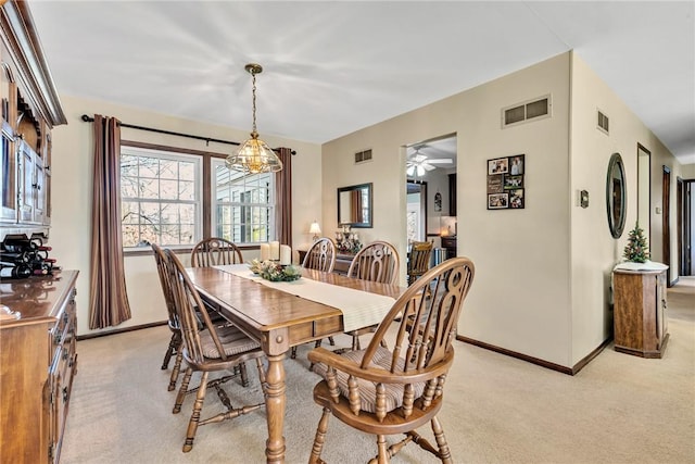 dining area featuring ceiling fan with notable chandelier and light colored carpet