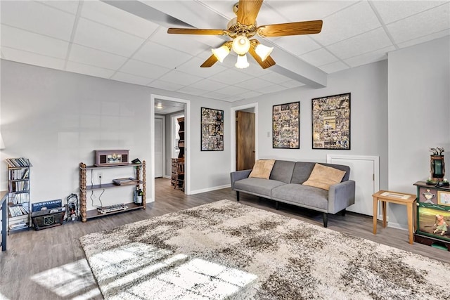 living room featuring ceiling fan, hardwood / wood-style floors, and a drop ceiling