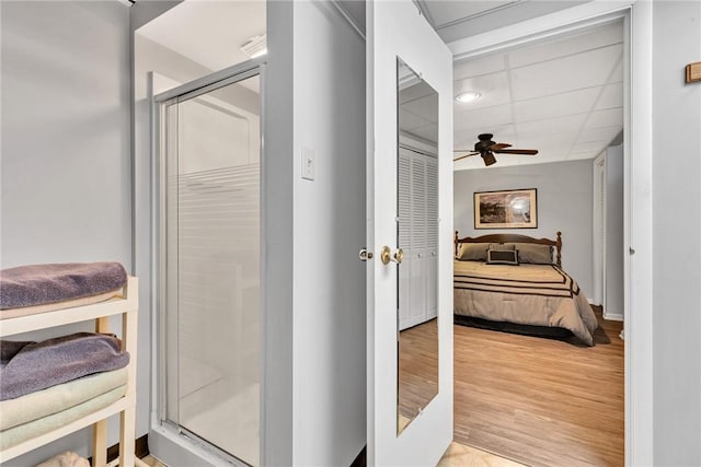 bathroom with ceiling fan, hardwood / wood-style floors, and a shower with shower door