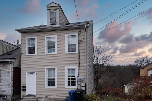 back house at dusk featuring cooling unit