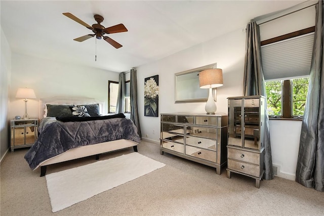 bedroom featuring light carpet, baseboards, and a ceiling fan