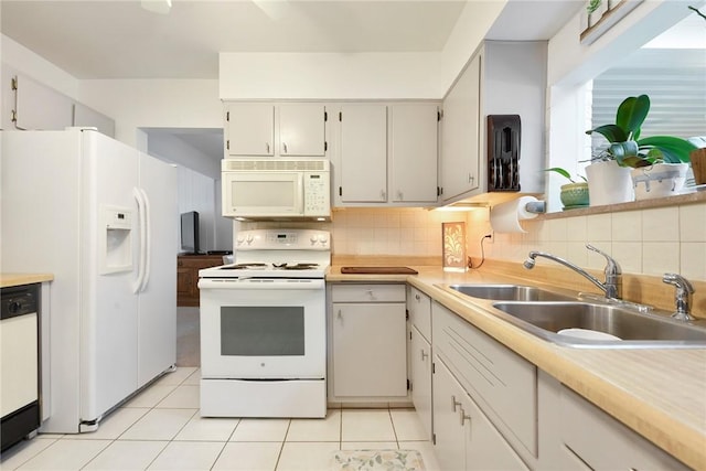 kitchen featuring white appliances, light countertops, a sink, and decorative backsplash