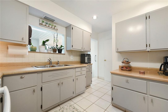 kitchen with light tile patterned floors, decorative backsplash, light countertops, and a sink