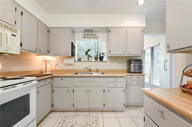 kitchen featuring tasteful backsplash, white appliances, light countertops, and a sink