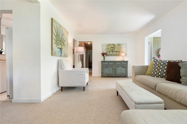 living area featuring light carpet and baseboards