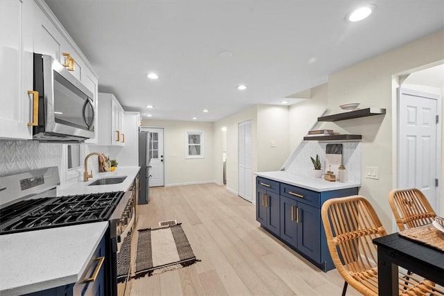 kitchen featuring blue cabinets, sink, light wood-type flooring, appliances with stainless steel finishes, and white cabinetry