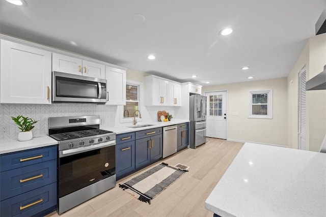 kitchen with blue cabinets, sink, white cabinets, and appliances with stainless steel finishes