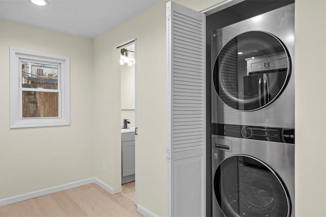 laundry area with stacked washer and clothes dryer and light wood-type flooring