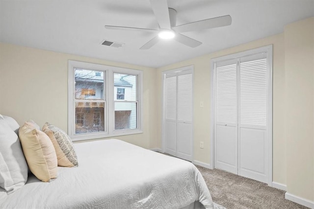 bedroom featuring carpet flooring, two closets, and ceiling fan