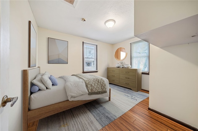 bedroom featuring light wood-type flooring, a textured ceiling, and multiple windows