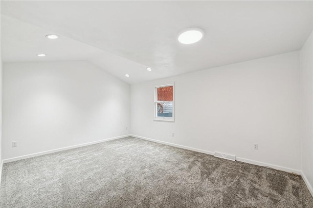 spare room featuring carpet floors and vaulted ceiling