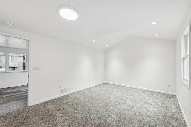 carpeted empty room featuring vaulted ceiling