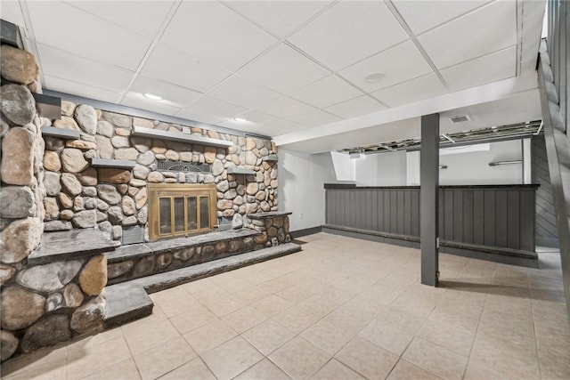 interior space featuring a fireplace, light tile patterned floors, and a drop ceiling