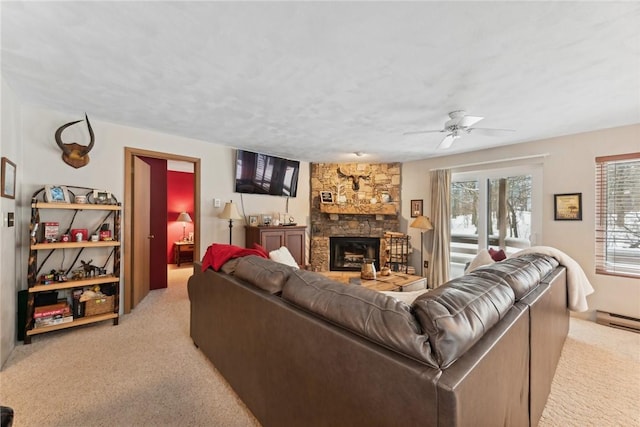 carpeted living room with a stone fireplace and ceiling fan