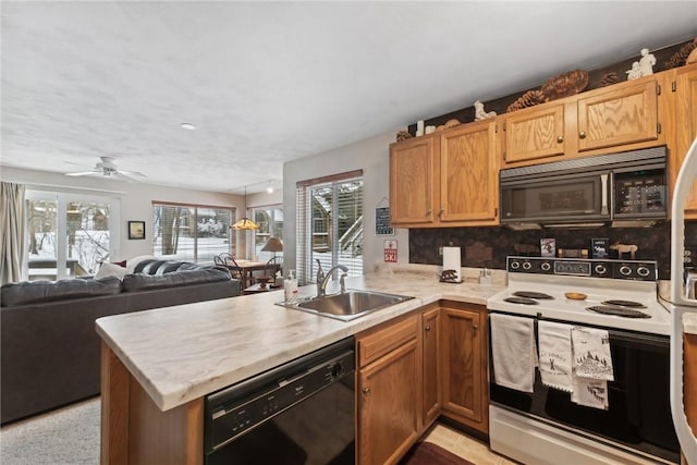 kitchen featuring kitchen peninsula, decorative backsplash, ceiling fan, sink, and black appliances