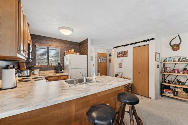 kitchen with kitchen peninsula, a breakfast bar, light colored carpet, sink, and white refrigerator