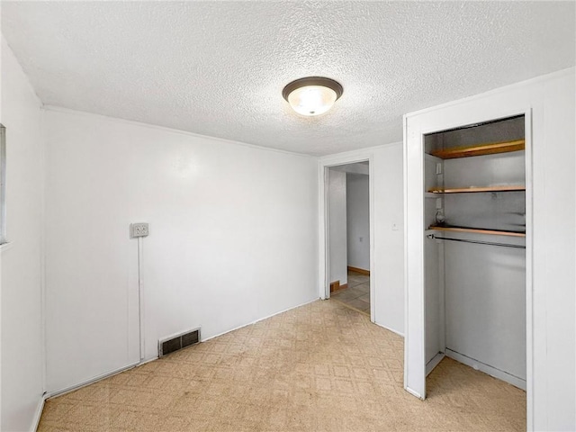 unfurnished bedroom featuring a closet, light colored carpet, and a textured ceiling