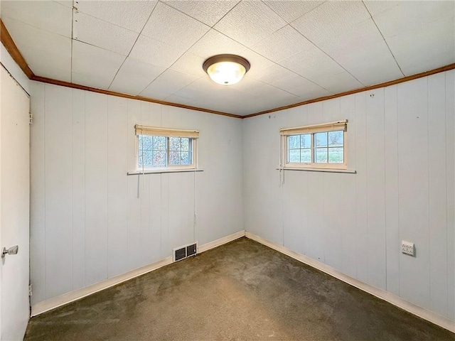 spare room featuring carpet flooring, wood walls, and ornamental molding