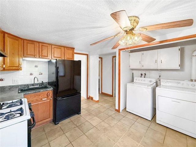 kitchen with black refrigerator, decorative backsplash, gas range gas stove, sink, and washer and dryer