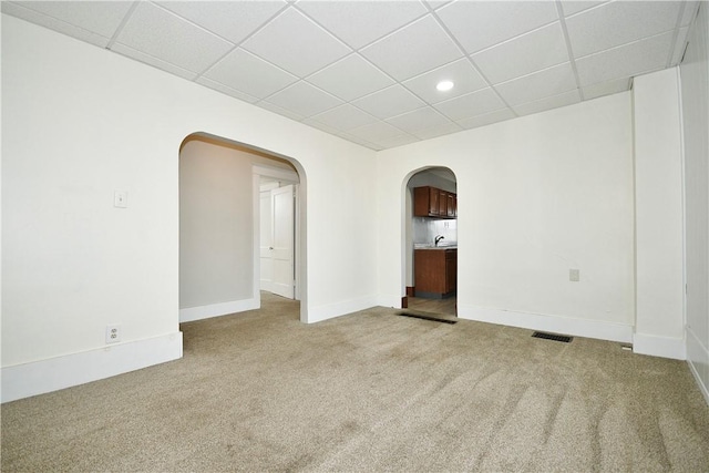 carpeted spare room with a drop ceiling and sink