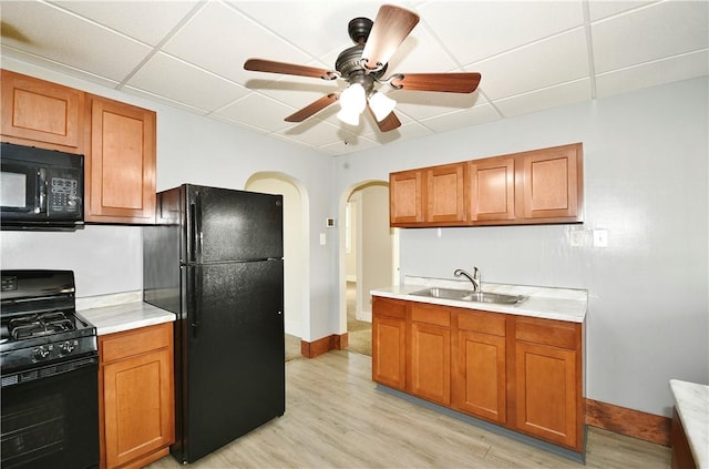 kitchen with ceiling fan, sink, light hardwood / wood-style floors, a paneled ceiling, and black appliances