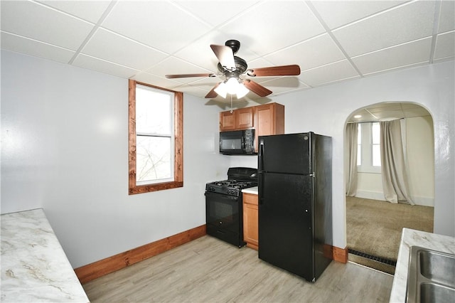 kitchen featuring black appliances, a drop ceiling, ceiling fan, and light wood-type flooring