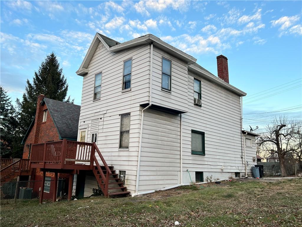 rear view of property with a wooden deck and a yard