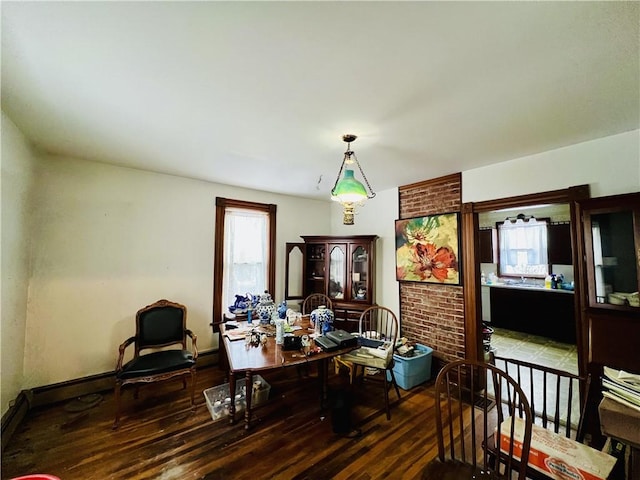 dining area featuring dark wood-type flooring and brick wall