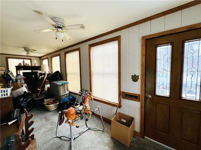 foyer with carpet, ceiling fan, and crown molding