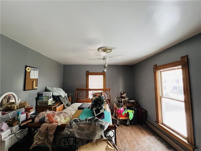 miscellaneous room featuring a wealth of natural light, ceiling fan, a baseboard heating unit, and light wood-type flooring