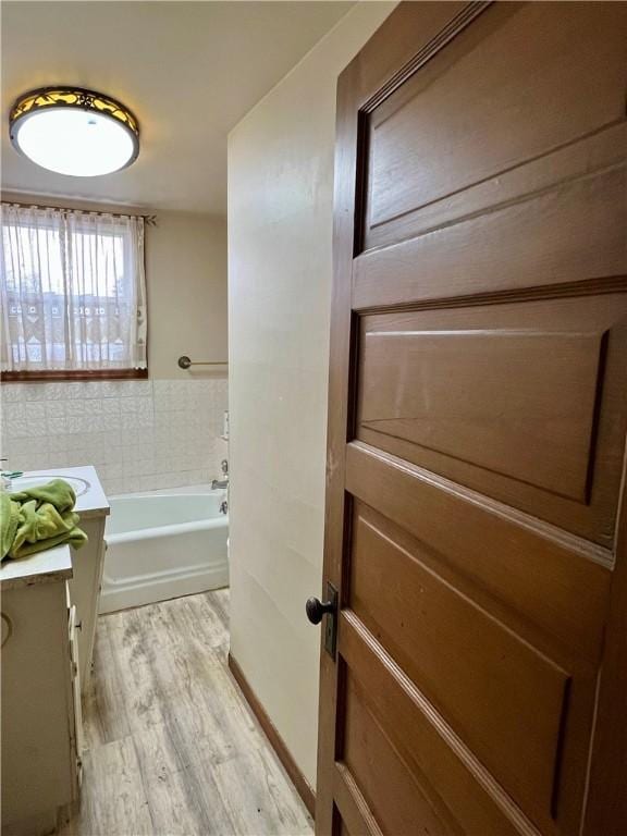 bathroom featuring hardwood / wood-style floors, vanity, and a tub to relax in