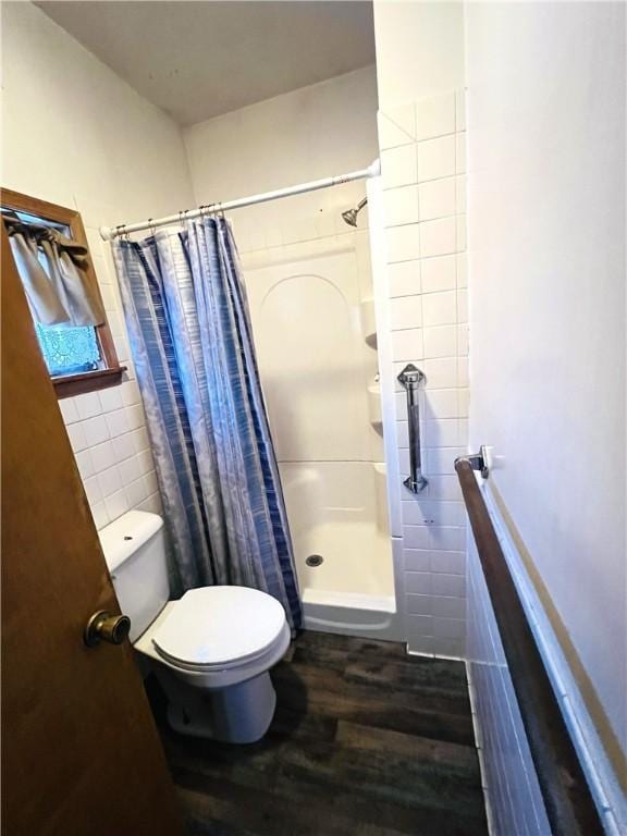 bathroom featuring a shower with shower curtain, toilet, wood-type flooring, and tile walls